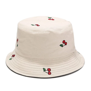Close-up of red cherry embroidery detail on off-white canvas bucket sun hat