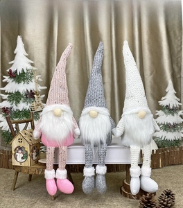 Three long-legged Christmas gnomes with knitted hats in pink, gray and white colors