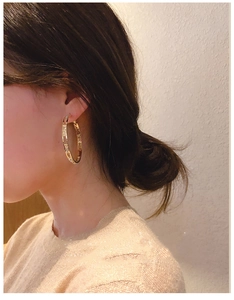 Close-up of model wearing gold hoop earrings with sparkling cubic zirconia inlay