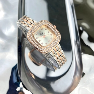 Close-up of square green watch dial with diamond-encrusted bezel and silver-gold band