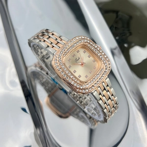 Macro detail of square green watch face with diamond bezel and two-tone metal strap