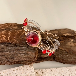 Detail of rose gold bracelet watch with red crystal dial on a natural stone background