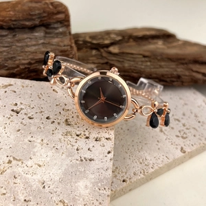 Detail of rose gold butterfly watch with blue gems on stone and wood base