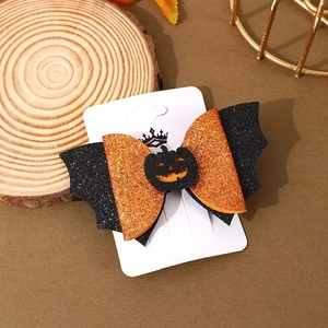 Detail of glitter Halloween bat hair clip with orange bow and pumpkin center on a card