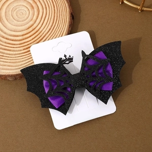 Detail of glittery black bat wing hair clip with spider web design and purple ribbon bow