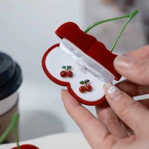 Pendientes de cereza brillantes en una caja de regalo de terciopelo rojo cereza