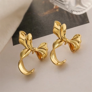Macro view of 18K gold plated bow earrings featuring elegant metallic ribbon textures