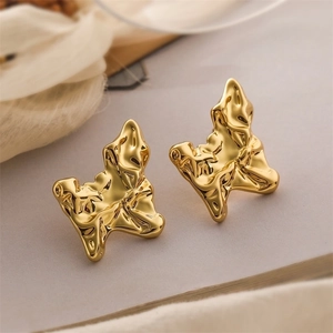 Detailed close-up of gold lava texture earrings on white fabric background