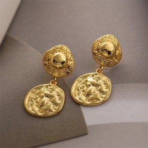 Macro detail of 18K gold plated vintage coin drop earrings with embossed relief texture