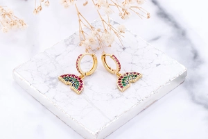 Detailed shot of gold hoop earrings with a rainbow arch pendant and multicolor zircons
