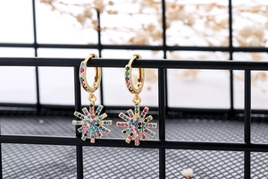 Macro detail of starburst drop earrings with multi-colored cubic zirconia on black mesh