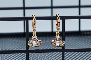 Detailed shot of gold crown earrings with rainbow cubic zirconia on a metal mesh display
