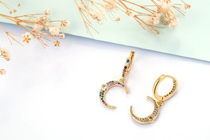 Detail of gold crescent moon earrings with colorful zircon stones in a macro shot