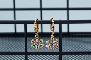 Macro shot of gold snowflake earrings with colorful zircon stones on metal mesh