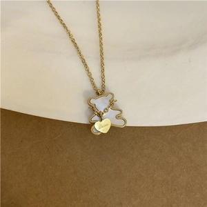 Gold bear pendant necklace with white shell inlay and Love heart charm on a delicate chain