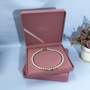Pink velvet jewelry box with white pearl necklace and gold letter pendant set