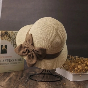 Straw sun hat with a brown linen bow and a ribbon on a vintage aesthetic background