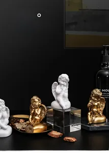 Détail rapproché des figurines d'anges en résine blanche et dorée sur fond élégant