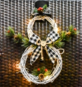 Close-up of snowman-shaped white rattan wreath with LED lights and plaid bow decoration