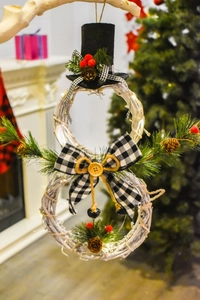 Detail of white rattan snowman Christmas wreath with pine cones and plaid bow decorations