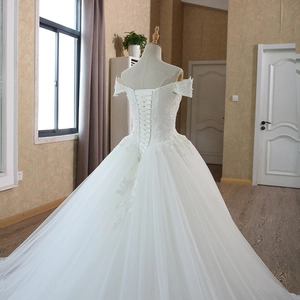 Elegant white off-shoulder lace wedding gown with a voluminous skirt and lace-up back detail