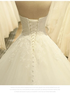 Dettaglio del corsetto con lacci e ricami sul retro di un abito da sposa bianco