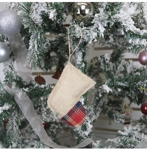 Détail d'une chaussette de Noël en toile avec motif à carreaux rouges sur un sapin enneigé