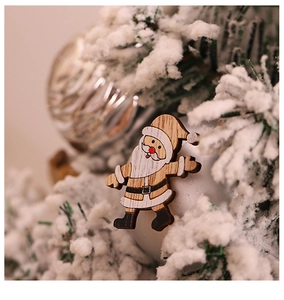 Detailed view of creative wooden Santa Claus ornament hanging on a snowy Christmas tree