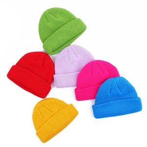 Knitted beanie hats in green red purple rose yellow and blue on white background