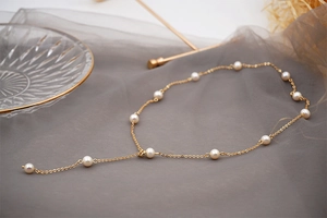Detail of adjustable gold Y-necklace featuring elegant freshwater pearls on soft tulle