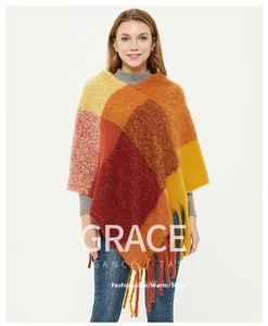 Detail of warm-toned plaid knit poncho featuring long fringe tassels for women