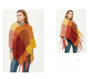 Detail of warm-toned plaid knit poncho with long fringe trim and vibrant orange checks