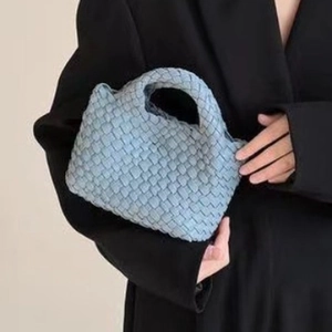 Mini light blue hand-woven bucket bag with a top handle shown on a model's outfit