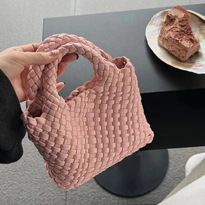 Detailed shot of a pink woven leather bucket bag featuring a seamless top handle grip
