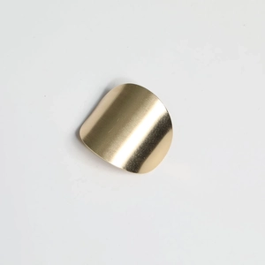 Detail view of the sleek curved golden metal hair hook with a smooth brushed finish texture