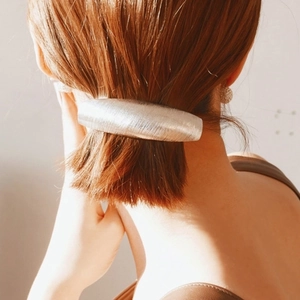 Close-up of matte silver hair clip with brushed metal texture on a low ponytail