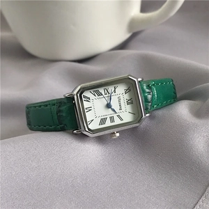 Detail view of a vintage square watch with green leather strap on silk fabric