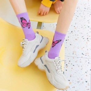 Close-up of purple mid-tube cotton socks with butterfly pattern and white sneakers