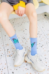 Detail view of light blue crew socks featuring a butterfly print on combed cotton fabric