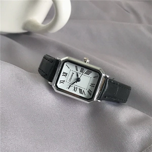 Detailed close-up of a silver rectangular watch case with white dial and Roman numerals