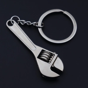 Detailed view of polished silver metal mini adjustable wrench keychain on black background
