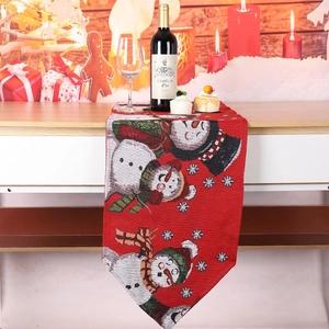 Close-up of red Christmas table runner with festive snowman patterns in a cozy dinner setup