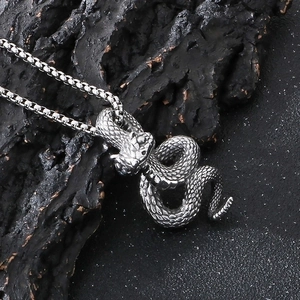 Detailed close-up of dark punk python snake pendant in vintage steel on rock background