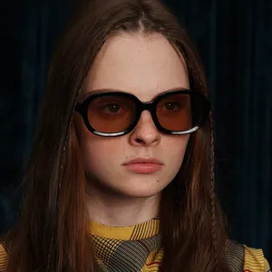 Close-up portrait of oval black frame sunglasses with amber lenses on a fashion model