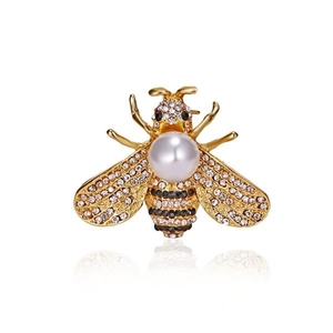Macro detail of a bee brooch with rhinestones and a white pearl on a gold-plated base