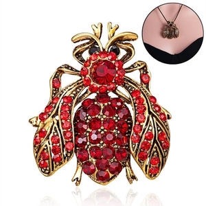 Macro detail of bee brooch featuring vintage gold finish and red rhinestone embellishments