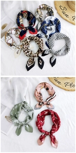 Close-up of assorted silk square scarves with leopard and chain prints on white fabric
