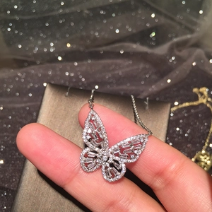 Dettaglio di un ciondolo a farfalla in argento traforato con pavé di zirconi lucidi