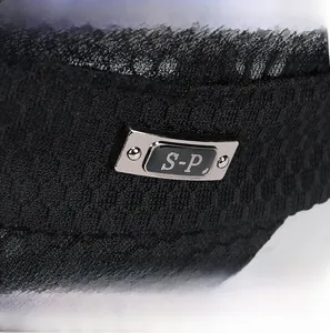 Detail of black mesh breathable fabric with silver metal logo plaque on a flat top cap
