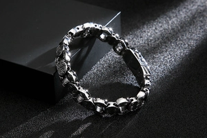 Détail de bracelet argenté vintage avec motif de croix en relief sur les maillons
